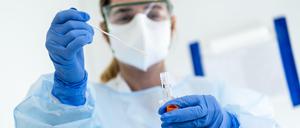 Laborantin mit Mund- und Körperschutz analysiert Coronatest.