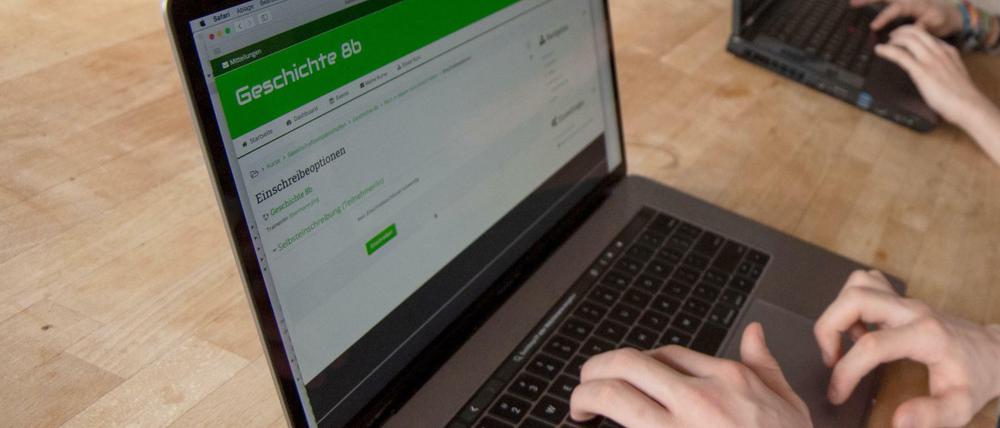 Auf einem Laptop ist ein Server für den Unterricht in "Geschichte 8 b" geöffnet, ein Jugendlicher loggt sich ein, zu sehen sind seine Hände.