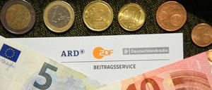 Auf einem Tisch liegt ein Anschreiben und Überweisungsträger für die Rundfunkgebühren, sowie der Betrag von 18 Euro und 36 Cent. 