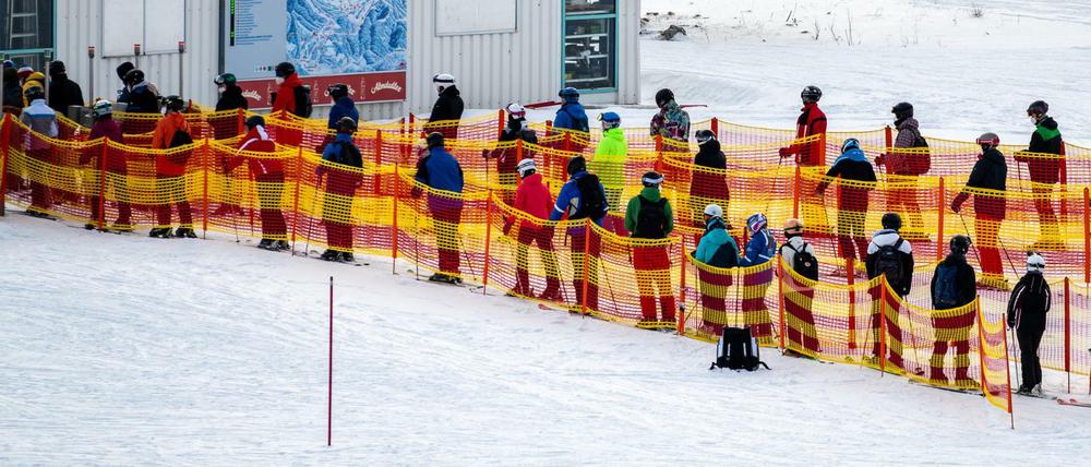 Skifahrer stehen an einem Skilift in Österreich in einer Schlange.