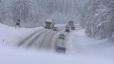 Autos fahren auf der schneeglatten Bundesstraße 12 in Bayern. 