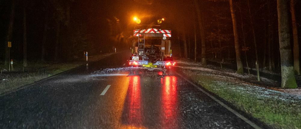Ein Winterdienstfahrzeug streut eine Bundesstraße.