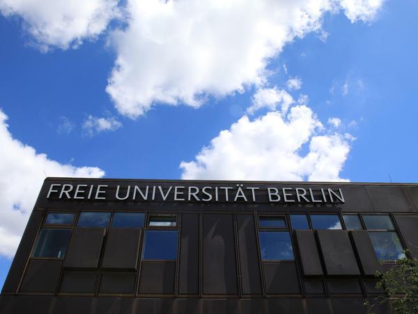 Schriftzug der FU an der Dachkante der "Rostlaube", darüber ein blauer Himmel mit weißen Wolken.