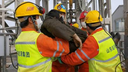 Ein Opfer des Minenunglücks in Qixia wird von Rettungskräften gestützt.