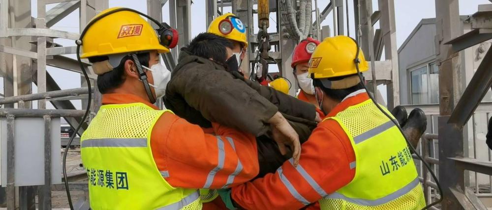Ein Opfer des Minenunglücks in Qixia wird von Rettungskräften gestützt.