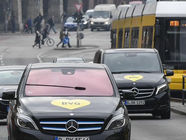 Vans des BVG-Ridesharing-Dienstes Berlkönig neben einer Straßenbahn in der Warschauer Straße.