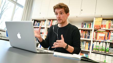 Ein Lehrer sitzt gestikulierend vor seinem IPad.