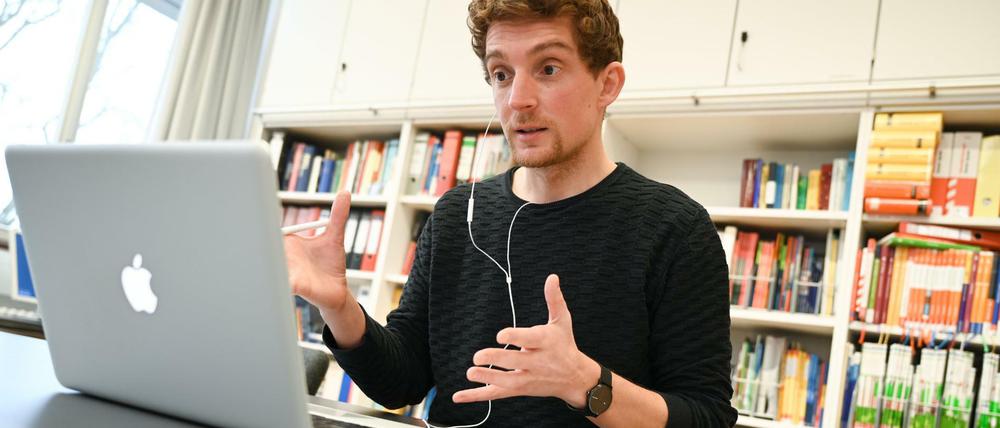 Ein Lehrer sitzt gestikulierend vor seinem IPad.