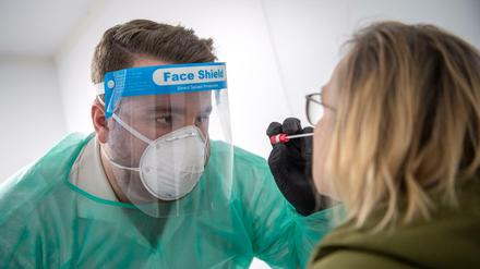 Ein Abstrich für einen PCR-Test wird von einem Mitarbeiter im Corona-Testzentrum genommen.