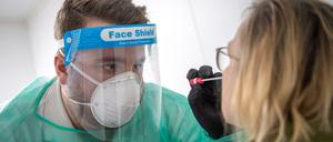 Ein Abstrich für einen PCR-Test wird von einem Mitarbeiter im Corona-Testzentrum genommen.