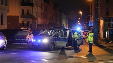 Polizisten stehen an einer durch ein Polizeifahrzeug blockierten Straße in Leipzig.