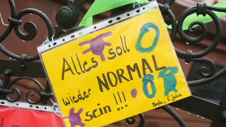 "Alles soll wieder normal sein" steht als Wunsch auf einem Blatt am Zaun einer Kita. 