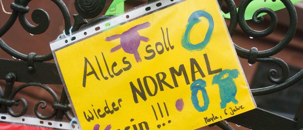 "Alles soll wieder normal sein" steht als Wunsch auf einem Blatt am Zaun einer Kita. 