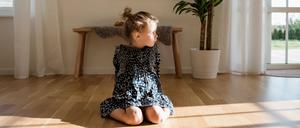portrait of a young girl sitting alone at home looking out the window