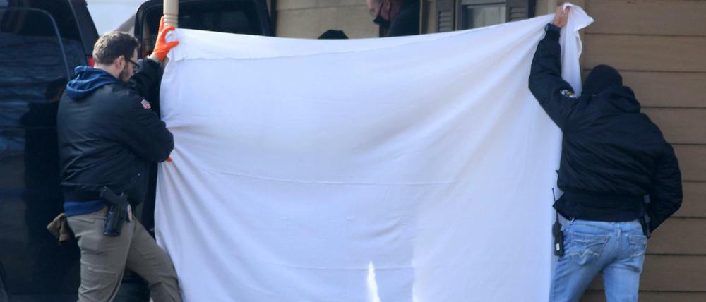 Ermittler versperren der Öffentlichkeit die Sicht, während die Leichen vom Tatort einer Schießerei entfernt werden. 