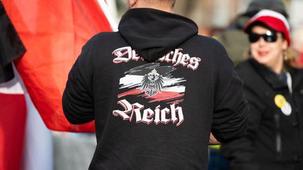 Ein Mann trägt einen Pullover mit dem Aufdruck "Deutsches Reich" bei einer Demonstration von Reichsbürgern.