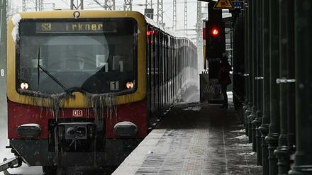 Eine S-Bahn der Linie S3 fährt an einem leeren Bahnhof durch den Schnee. 