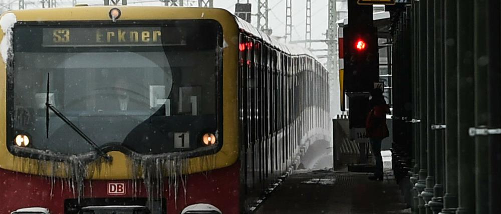 Eine S-Bahn der Linie S3 fährt an einem leeren Bahnhof durch den Schnee. 