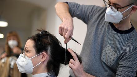 Ein Friseur schneidet einer Kundin in seinem Salon die Haare