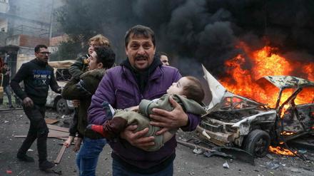 Ein Mann trägt sein Kind in Aleppo in Syrien.