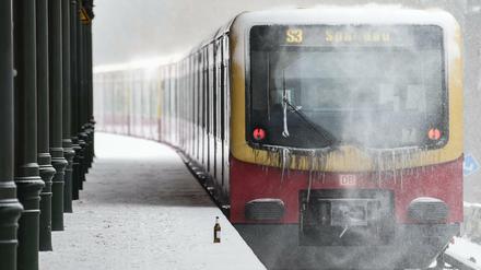 Die S-Bahnlinie S3 nach Spandau fährt an einem Bahnhof durch den Schnee.