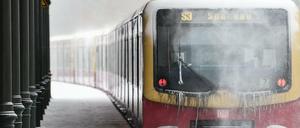 Die S-Bahnlinie S3 nach Spandau fährt an einem Bahnhof durch den Schnee.