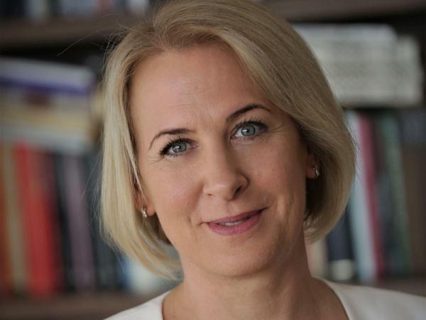 Eine Professorin steht vor ihrem Bücherregal im Arbeitszimmer.