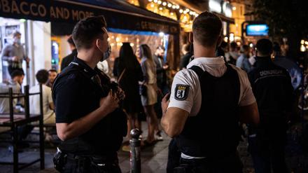 Ein Polizeibeamter und ein Mitarbeiter des Ordnungsamtes stehen vor einem Lokal in Berlin.