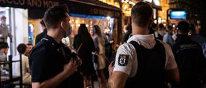 Ein Polizeibeamter und ein Mitarbeiter des Ordnungsamtes stehen vor einem Lokal in Berlin.