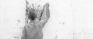 Gerhard Richter hängt ein Bild an die Wand seines Kölner Ateliers, 1990.