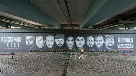 Eine Frau geht vor den Porträts von Opfern des Anschlags von Hanau entlang, die unter die Frankfurter Friedensbrücke gemalt wurden.