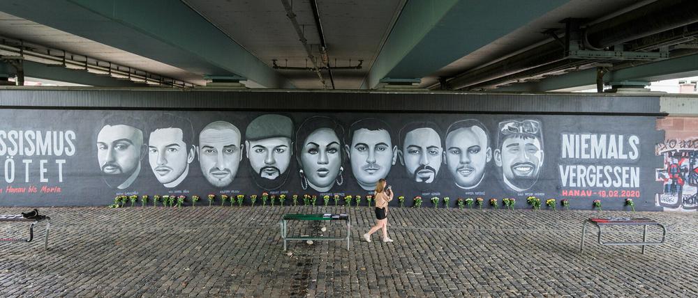 Eine Frau geht vor den Porträts von Opfern des Anschlags von Hanau entlang, die unter die Frankfurter Friedensbrücke gemalt wurden.