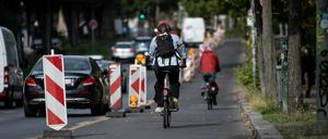 Radfahrer sind auf dem Pop-up-Radweg am Halleschen Ufer unterwegs, während ein Pkw verbotswidrig auf der Fahrbahn daneben parkt.