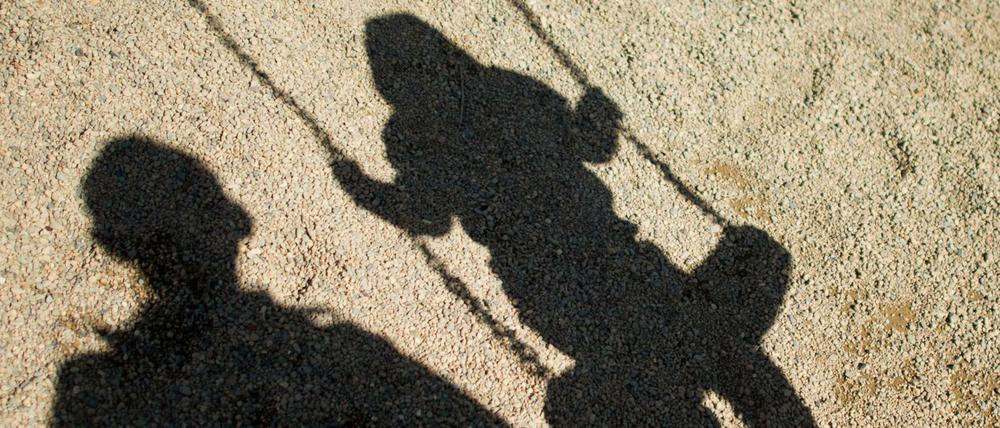 Der Schatten von einem Mann und einem schaukelnden Kind (Symbolfoto).