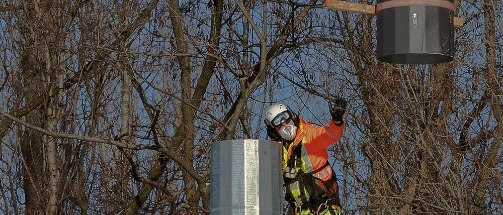 Der Mast kommt aus der Luft. Ein Arbeiter montiert die Teile eines Flutlichtmasts im Poststadion an der Lehrter Straße zusammen, geliefert vom Hubschrauber.