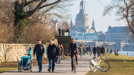 Menschen nutzen das Frühlingswetter und genießen die ersten Sonnenstrahlen am Elbufer in Dresden.
