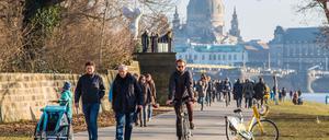 Menschen nutzen das Frühlingswetter und genießen die ersten Sonnenstrahlen am Elbufer in Dresden.