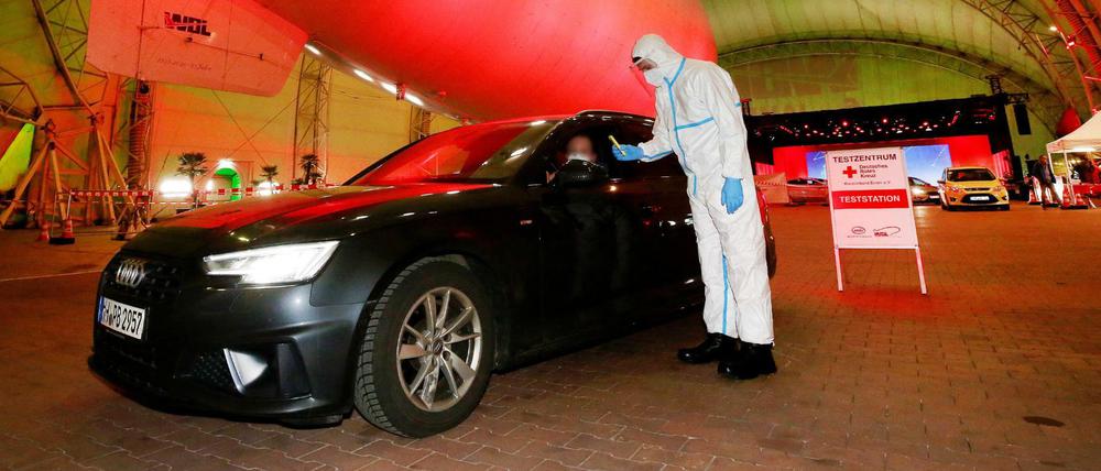 Im Luftschiffhangar des Flughafens Essen/Mülheim führt ein Rote Kreuz-Mitarbeiter im Drive-In-Testzentrum einen Corona-Schnelltest durch.