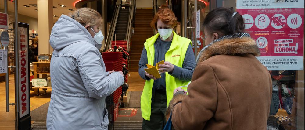 Eine Mitarbeiterin kontrolliert am Eingang eines Kaufhauses Impfnachweise von Kunden.