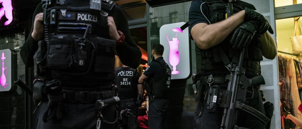 Polizeibeamte stehen bei einer großen Kontrollaktion in Neukölln vor einem gastronomischen Betrieb.