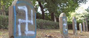 Grabsteine auf einem jüdischen Friedhof sind mit Hakenkreuzsymbolen beschmiert.
