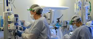  Intensivpflegerinnen sind auf der Covid-19-Intensivstation einer Klinik mit der Versorgung von Patienten beschäftigt.