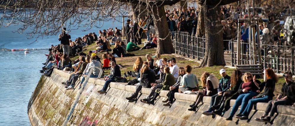 Menschen genießen am Landwehrkanal in Berin-Kreuzberg die Sonne.