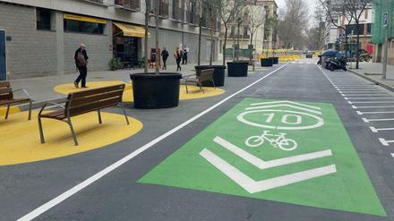 Autofreier Superblock in Barcelona mit Bänken, Bäumen und teils grün gefärbter Fahrradspur.