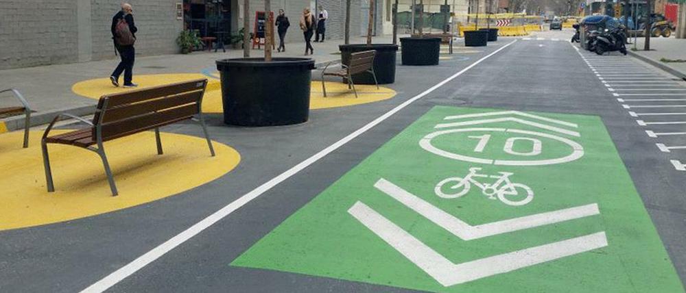 Autofreier Superblock in Barcelona mit Bänken, Bäumen und teils grün gefärbter Fahrradspur.