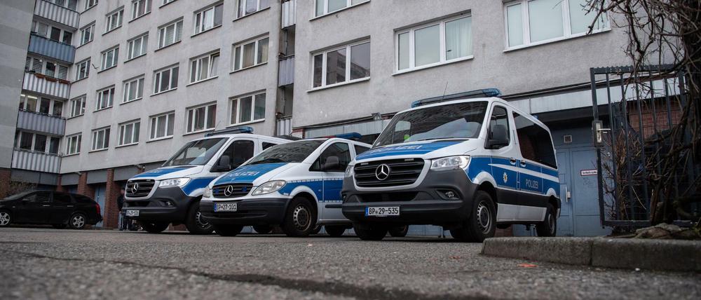 Einsatzfahrzeuge der Polizei bei der Razzia in Berlin-Lichtenberg vor einem Wohnhaus.