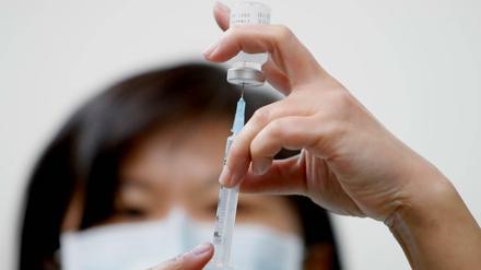 Eine Krankenschwester zieht Impfstoff in eine Spritze.