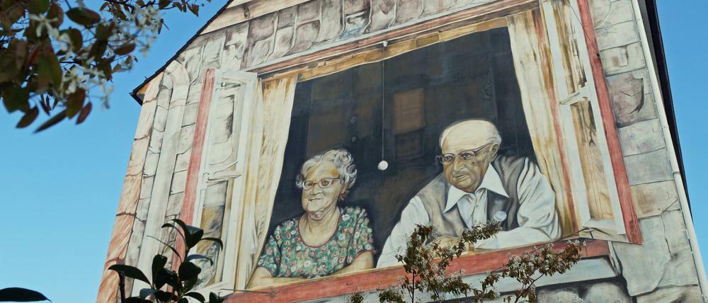 Dieses Wandbild an einer zeigt ein altes Ehepaar beim Blick aus dem Fenster auf den Rembertikreisel in Bremen. Der Künstler Peter K. F. Krüger malte das Bild 1976, um die Sehnsucht nach dem ursprünglichen Stadtbild auszudrücken. Im Ostertorviertel waren damals alte Häuser abgerissen worden, um Platz für die sogenannte Mozarttrasse zu schaffen. Zur Trasse kam es nicht. Auch in Bremen leben die meisten Menschen nicht in Einfamilienhäuser, sondern in einer Etagenwohnung. Das Glück ist nicht immer vollkommen, wenn diese Wohnung Eigentum ist: In der Gemeinschaft regiert immer der Kompromiss. 