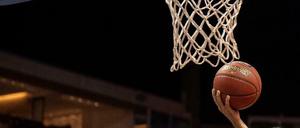 Hand mit Basketball unter Basketballkorb.
