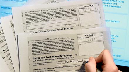 Eine Frau, deren Hand zu sehen ist, füllt einen Bafög-Antrag auf Papier aus.